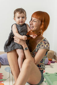 Redheaded mother having some fun and playing her baby girl daugh