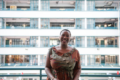 Smiling young woman standing against building in city