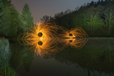 Reflection of light painting in lake against sky at night