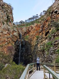 Rear view of man standing on railing by mountain