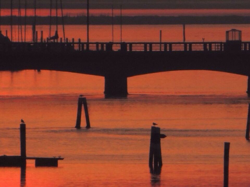 sunset, water, silhouette, built structure, orange color, architecture, sea, waterfront, reflection, connection, river, bridge - man made structure, tranquil scene, sky, tranquility, pier, scenics, beauty in nature, nature, rippled