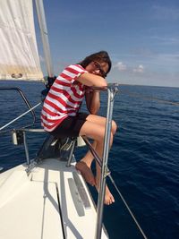 Side view portrait of woman sitting on boat in sea against sky