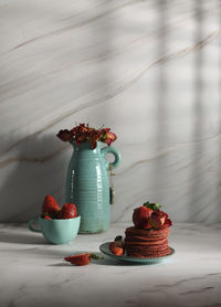 Still life with pink strawberry pancakes on a turquoise plate with sour cream