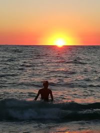 Silhouette man on beach against sky during sunset