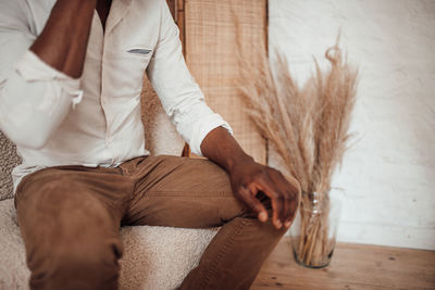 Midsection of man sitting on sofa at home