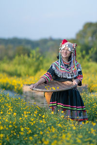 Rear view of woman with yellow flowers on field