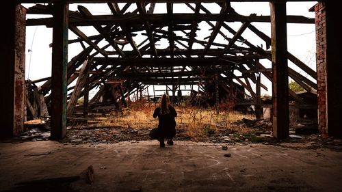 Rear view of woman sitting in abandoned building