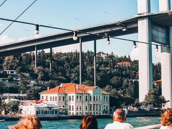 Bridge over river by buildings in city against sky