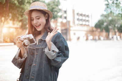 Young woman photographing with camera in city