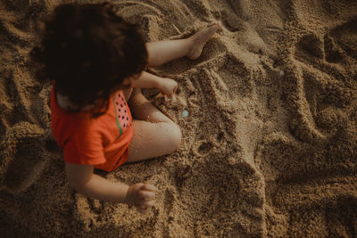 High angle view of girl relaxing on sand at beach