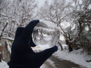 Close-up of hand holding crystal ball on snow