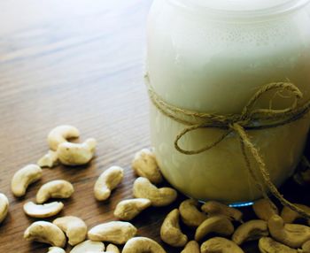 Close-up of drink in glass jar with cashews on table