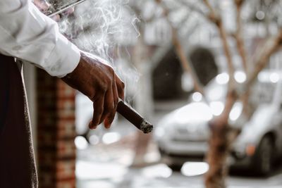 Midsection of man holding cigarette