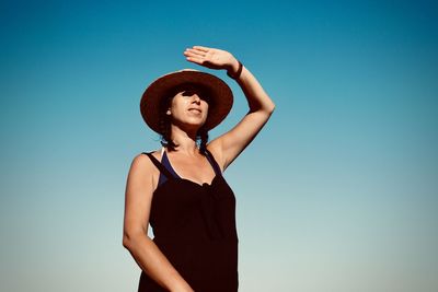 Low angle view of woman standing against clear blue sky