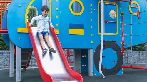 Full length of boy sliding in playground