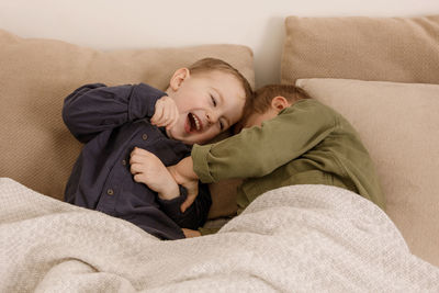 Two little and cute caucasian boys playing together on the bed at home.