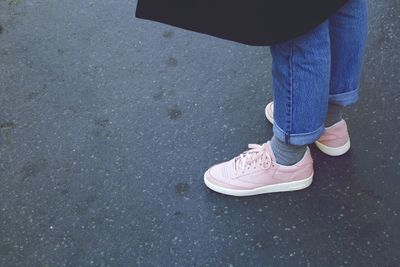 Low section of woman wearing pink shoes on road