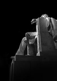 Rear view of man sitting against black background