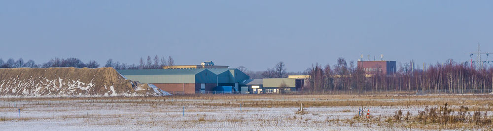 Houses on field against clear sky during winter