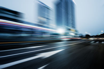 Light trails on street amidst buildings in city at night