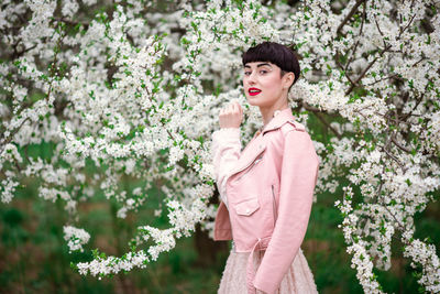 Woman standing by pink flowering tree