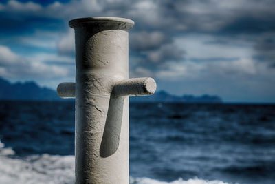 Close-up of wooden post at beach against sky