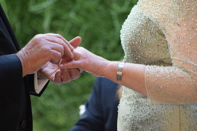 Midsection of couple exchanging engagement ring