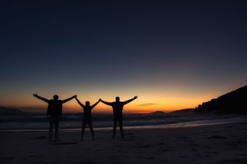Silhouette people standing at beach against clear sky during sunset