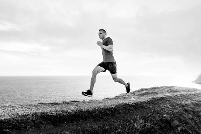 Full length of man jumping in sea against sky