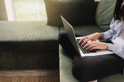 Man using mobile phone while sitting on sofa at home