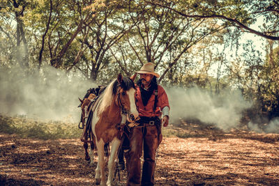 Man standing by horse in forest