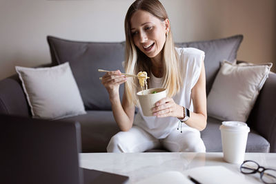 Young woman sitting on sofa at home