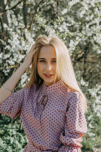 Blonde girl on a spring walk in the garden with cherry blossoms. female portrait, close-up. 