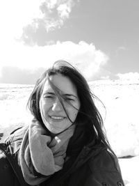 Portrait of smiling young woman in snow against sky
