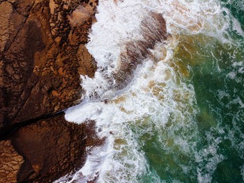 Aerial top view of sea waves hitting rocks on the cliffs. overhead foamy sea waves splashing 