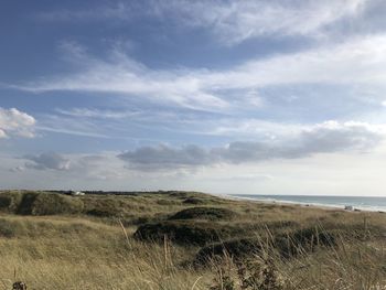 Scenic view of sand dunes and sea against sky