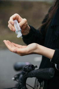 Midsection of woman taking sanitizer on hand