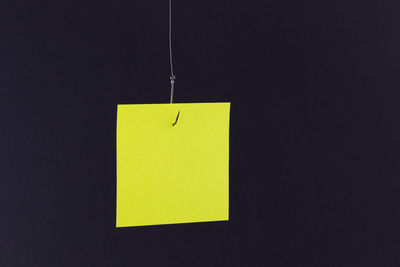 Close-up of yellow paper hanging against black background
