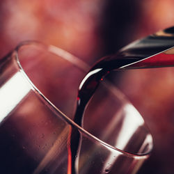 Red wine pouring into wine glass, close-up.