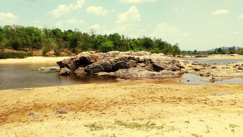 Scenic view of rocks on shore against sky