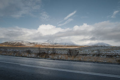 Road by mountains against sky