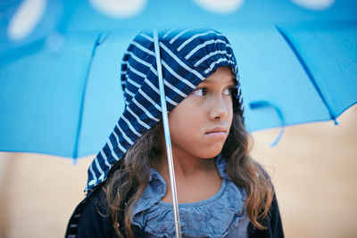 Girl with umbrella looking away during rainy season
