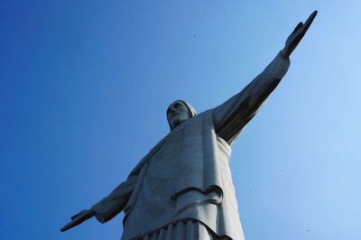 Low angle view of jesus statue against clear blue sky