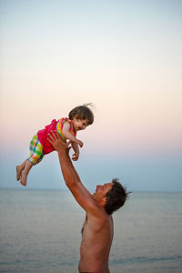 Father and son on beach against clear sky