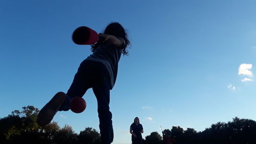 Low angle view of men playing with ball against sky