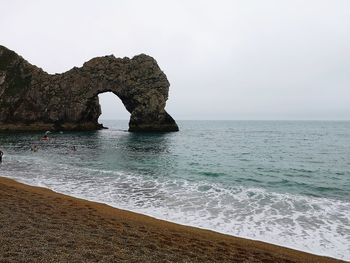 Rock formation in sea against sky