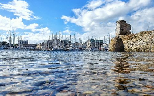 View of harbor by river against sky