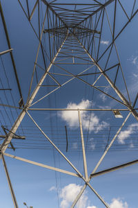 Low angle view of electricity pylon against blue sky