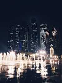 Illuminated buildings against sky at night