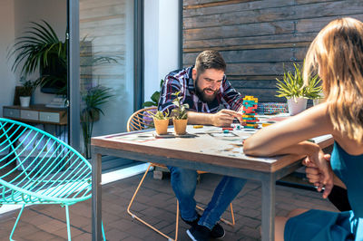 Bearded man catching jenga game piece with colleague on terrace